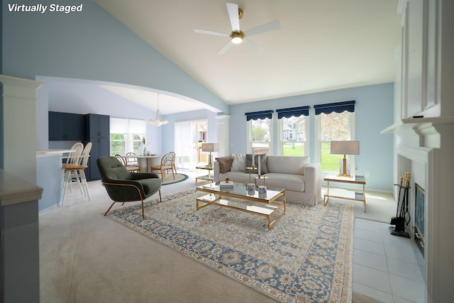 living room featuring arched walkways, ceiling fan, light carpet, and lofted ceiling