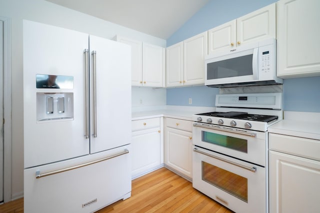 kitchen featuring light countertops, vaulted ceiling, white appliances, and white cabinetry
