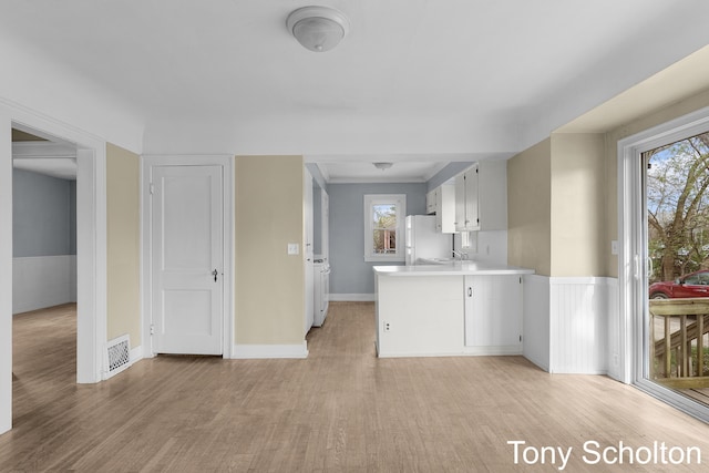 kitchen with visible vents, freestanding refrigerator, light wood finished floors, and light countertops
