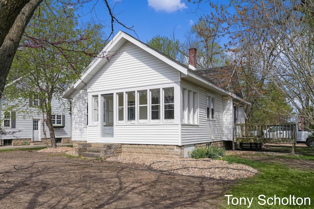 view of side of property with a chimney, a deck, and entry steps