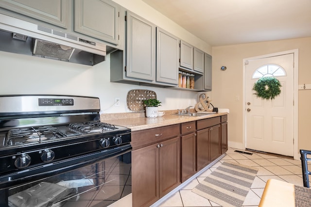 710 Robinwood St, Pontiac, MI 48340 - kitchen featuring black gas stove, under cabinet range hood, a sink, light countertops, and light tile patterned flooring