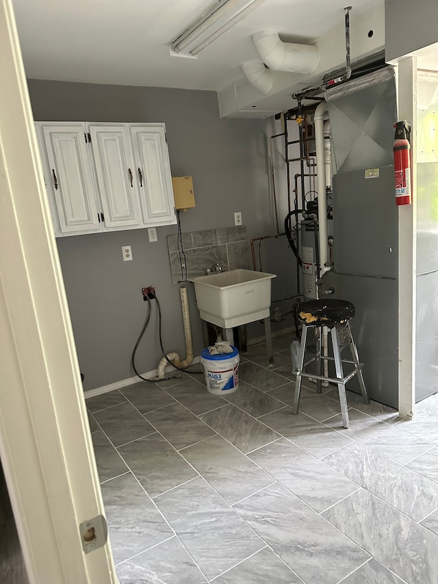 laundry room with gas water heater, a sink, and heating unit