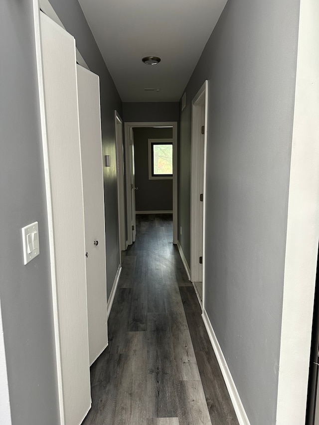 hall featuring dark wood-style flooring and baseboards
