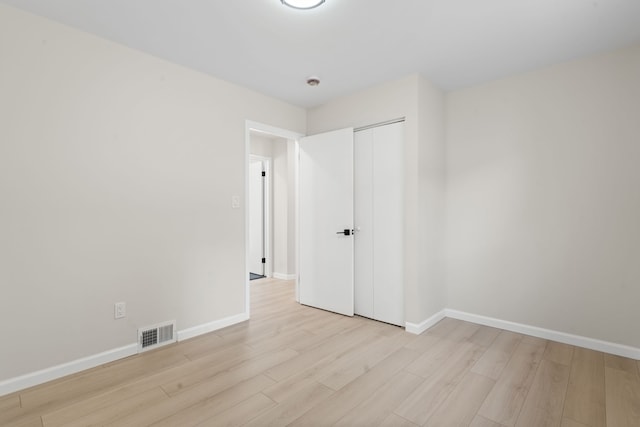 unfurnished bedroom with light wood-style flooring, baseboards, and a closet