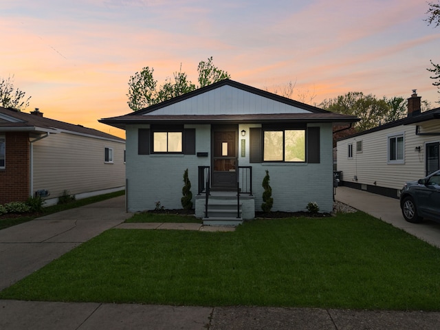 bungalow-style house with brick siding and a lawn