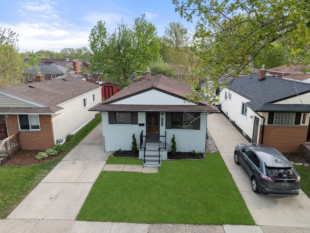bungalow-style home featuring concrete driveway, a front lawn, and brick siding