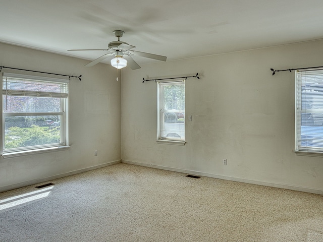 empty room with visible vents, ceiling fan, and a wealth of natural light