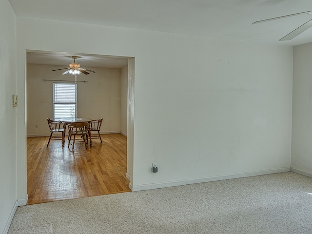 unfurnished dining area with baseboards, a ceiling fan, and wood finished floors