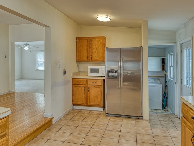 kitchen featuring washer / clothes dryer, brown cabinetry, stainless steel fridge with ice dispenser, and white microwave