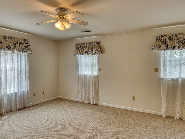 empty room featuring visible vents, a ceiling fan, baseboards, and light colored carpet