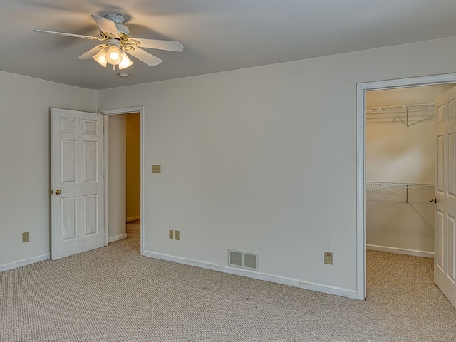 unfurnished bedroom featuring visible vents, a walk in closet, a closet, and light carpet