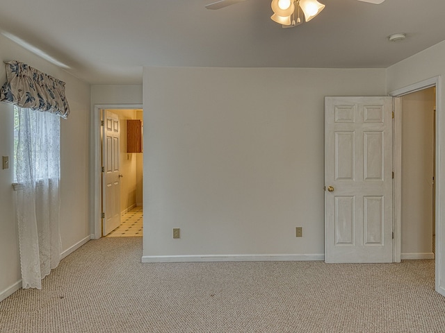 unfurnished bedroom featuring baseboards, light carpet, and ensuite bath