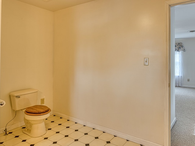 half bathroom with baseboards, tile patterned floors, and toilet