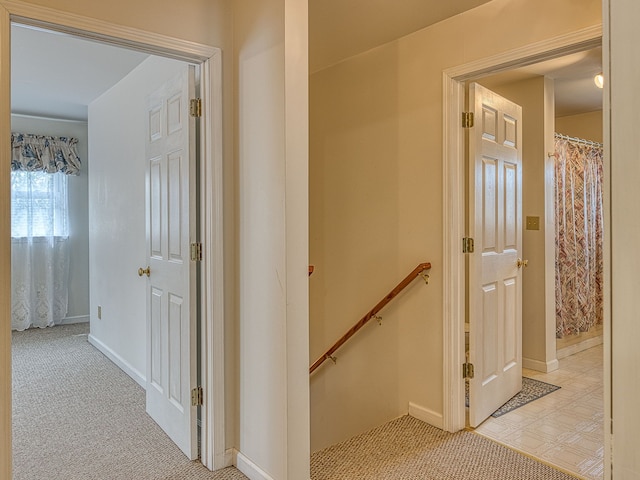 corridor with baseboards, carpet, and an upstairs landing
