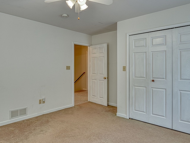 unfurnished bedroom with visible vents, a closet, light carpet, baseboards, and a ceiling fan