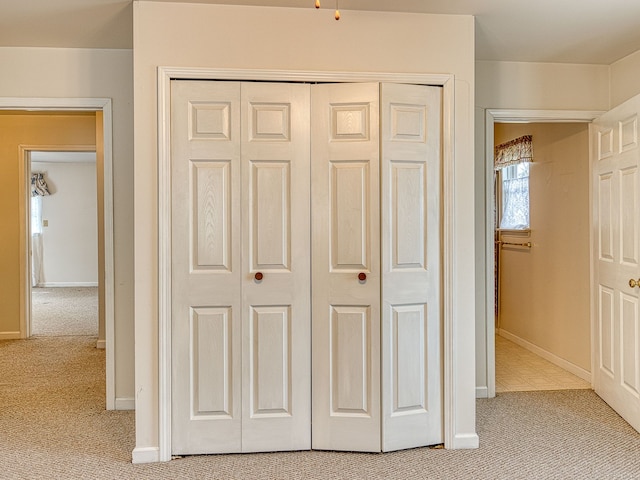 unfurnished bedroom featuring a closet, baseboards, and light carpet