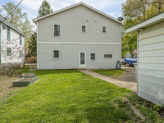 back of house featuring a lawn and a vegetable garden
