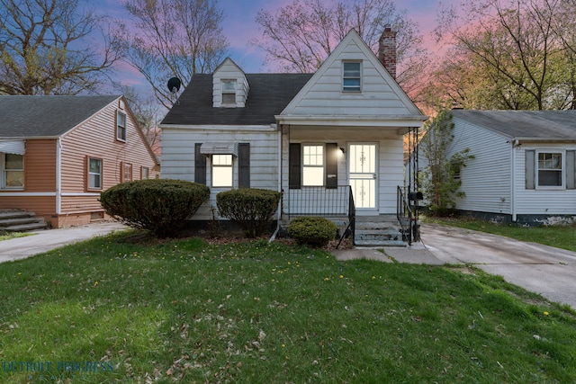 view of front of house featuring a porch, a lawn, and a chimney