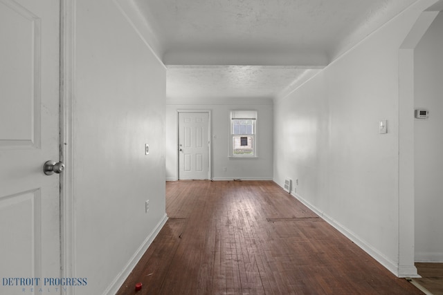 interior space with arched walkways, baseboards, visible vents, and hardwood / wood-style flooring