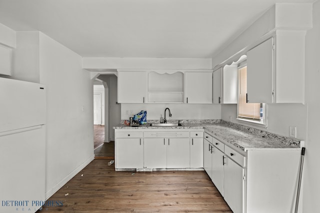 kitchen featuring open shelves, freestanding refrigerator, wood finished floors, white cabinets, and a sink