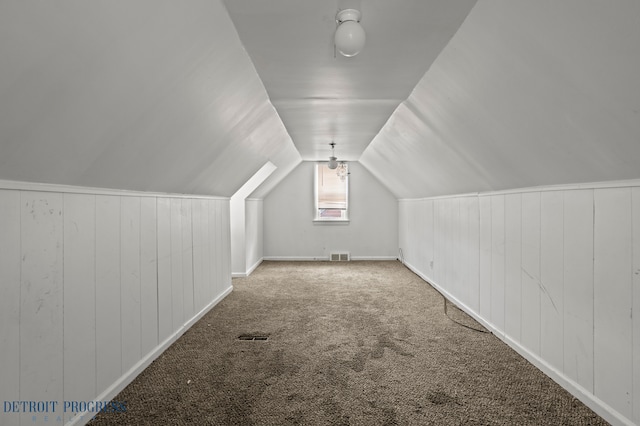 bonus room with visible vents, vaulted ceiling, baseboards, wooden walls, and carpet