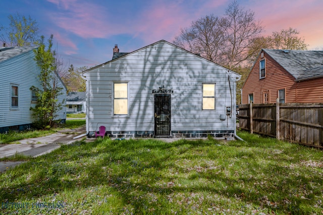 back of property featuring fence, a chimney, and a yard