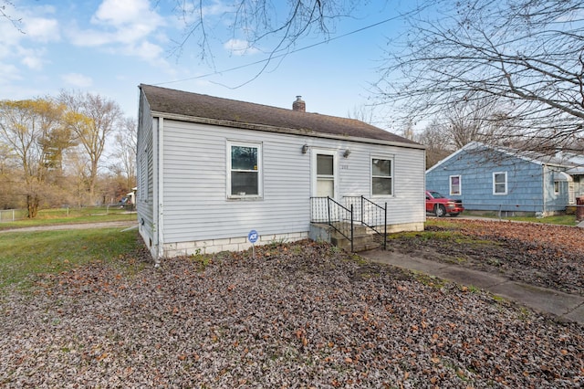 bungalow-style home with roof with shingles and a chimney