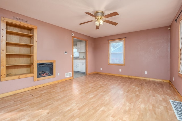 unfurnished living room featuring baseboards, ceiling fan, visible vents, and wood finished floors