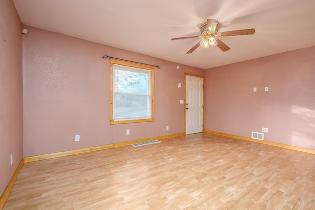 empty room featuring light wood-style floors, baseboards, a ceiling fan, and visible vents