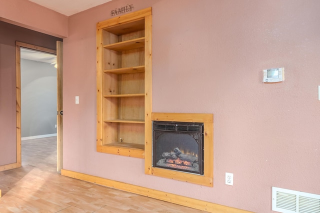 room details featuring baseboards, a fireplace, wood finished floors, and visible vents
