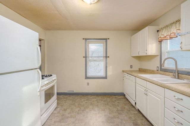 kitchen featuring white appliances, white cabinets, visible vents, and a sink