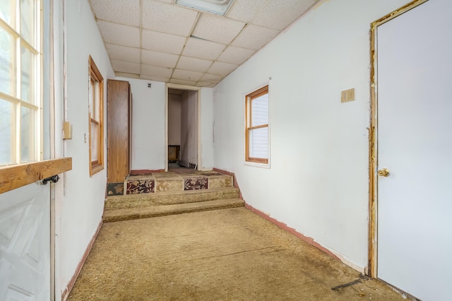 hallway with baseboards, a drop ceiling, carpet flooring, and stairs