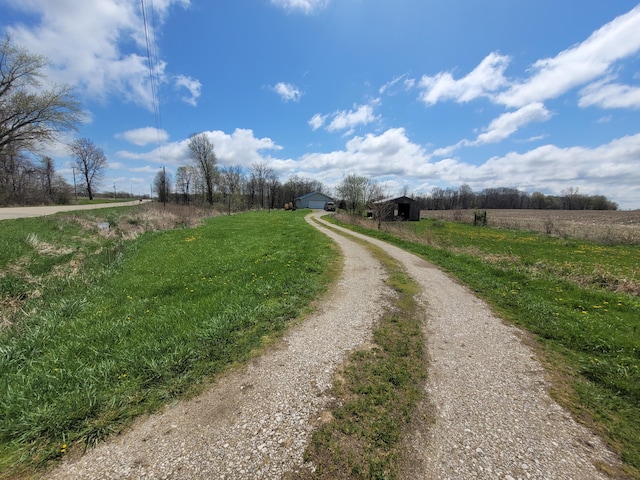 view of street with driveway and a rural view