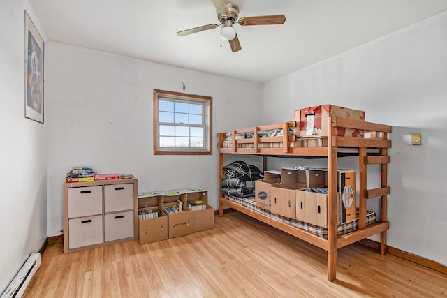 bedroom with baseboards, baseboard heating, and wood finished floors