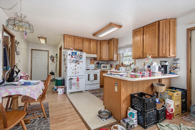 kitchen with a peninsula, white appliances, light wood-style floors, light countertops, and under cabinet range hood