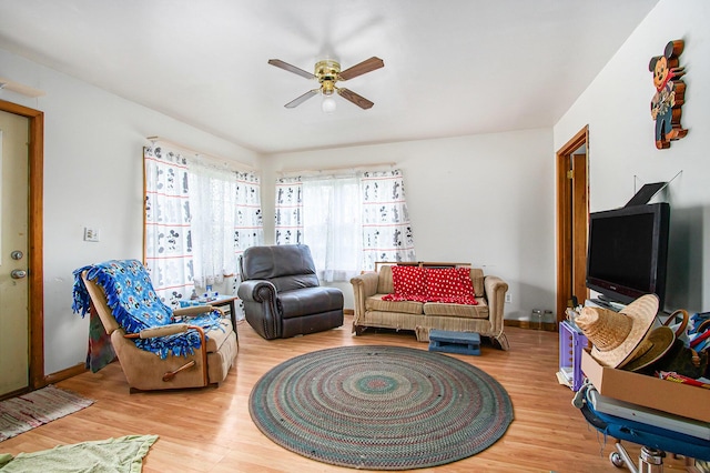 living area featuring baseboards, ceiling fan, and wood finished floors