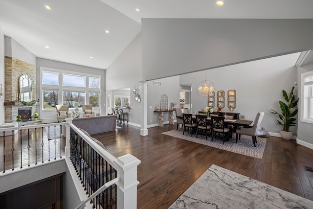 living room with wood-type flooring, baseboards, a notable chandelier, and high vaulted ceiling