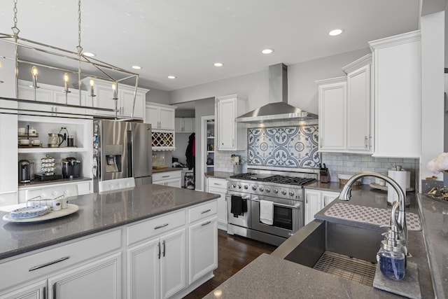 kitchen with wall chimney range hood, a sink, stainless steel appliances, white cabinetry, and tasteful backsplash