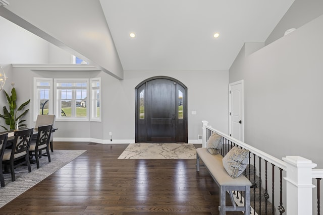 foyer entrance featuring high vaulted ceiling, baseboards, wood-type flooring, and arched walkways