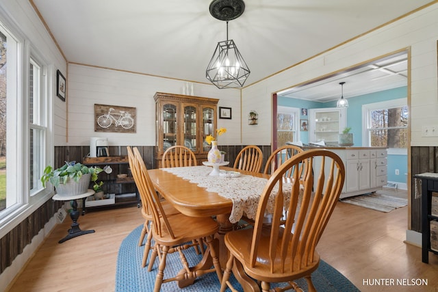 dining room featuring wooden walls, light wood-style floors, and a chandelier