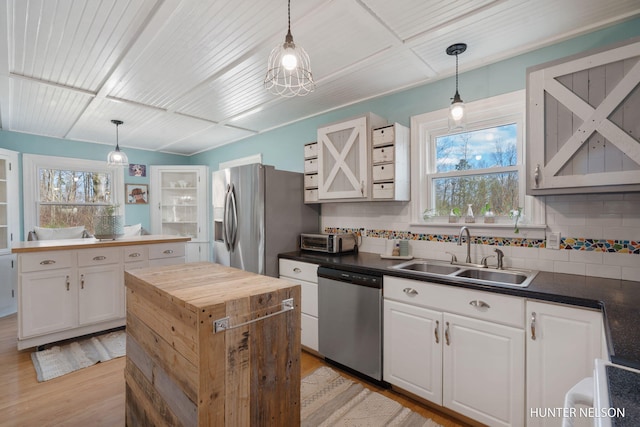 kitchen featuring appliances with stainless steel finishes, butcher block counters, a sink, and tasteful backsplash