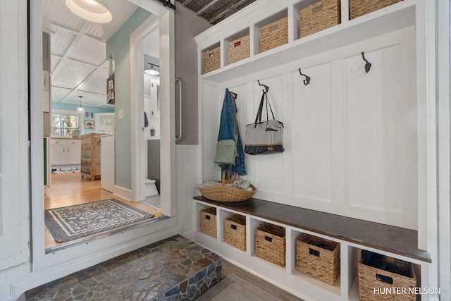 mudroom with a decorative wall, dark wood finished floors, and a wainscoted wall