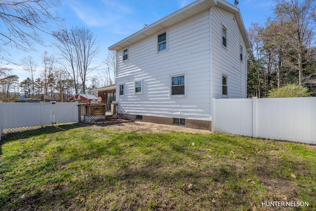 rear view of house with a gate, fence, and a yard