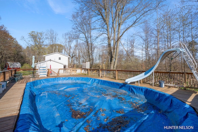 view of pool with a water slide and a deck