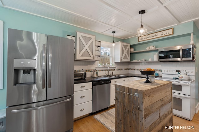 kitchen with a sink, light wood-style flooring, appliances with stainless steel finishes, and tasteful backsplash