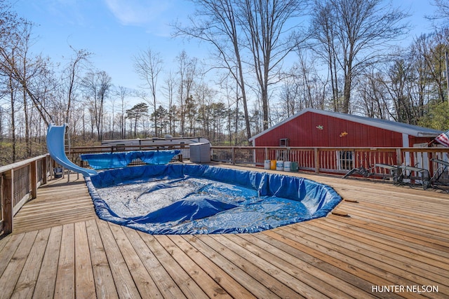 view of pool with a covered pool, a water slide, and a deck