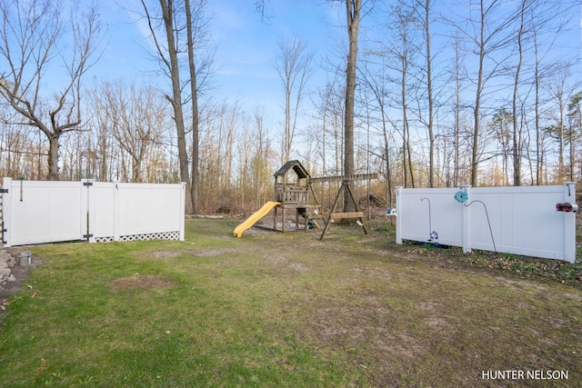 view of yard with a gate, a playground, and fence