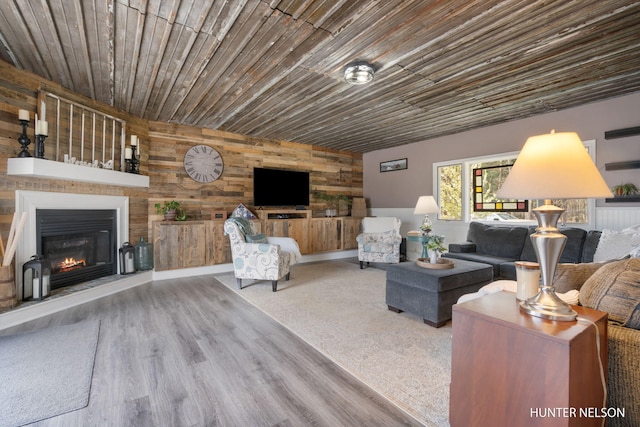 living area with a glass covered fireplace, wood ceiling, wood walls, and wood finished floors