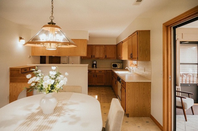 kitchen with decorative backsplash, decorative light fixtures, light countertops, a sink, and white microwave
