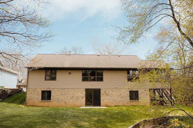 back of property with stairs, a shingled roof, a yard, and brick siding